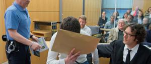 Der Angeklagte Sanel M. wird am 24.04.2015 zu Verhandlungsbeginn in einen Sicherheitssaal des Landgerichts in Darmstadt geführt und nimmt neben seinem Anwalt Stephan Kuhn (r) Platz.