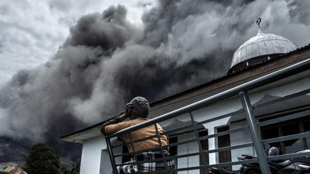 Eine Frau in Indonesien schaut auf die Rauchschwaden des Sinabung. Seit dem Ausbruch des Vulkans auf der Insel Sumatra haben mehr als 10.000 Menschen ihre Häuser verlassen.