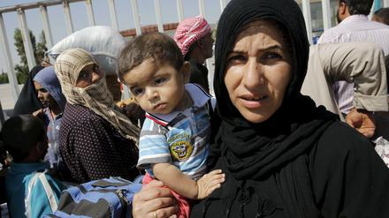 Weg vom Krieg. Eine Syrerin mit ihrem Kind an der türkisch-syrischen Grenze.