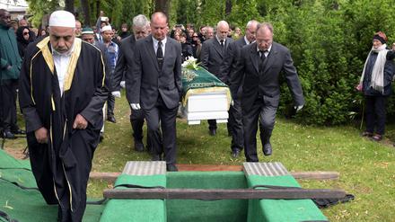 Imam Abdallah Hajjir (l) geht vor dem Sarg mit den sterblichen Überresten eines 60-jährigen Flüchtlings auf dem Friedhof Alter Zwölf-Apostel-Kirchhof in Berlin zur Grabstätte.