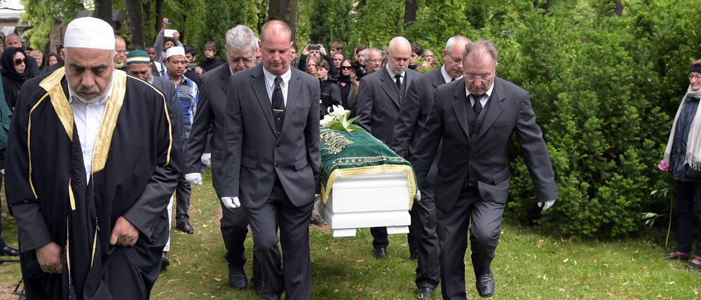Imam Abdallah Hajjir (l) geht vor dem Sarg mit den sterblichen Überresten eines 60-jährigen Flüchtlings auf dem Friedhof Alter Zwölf-Apostel-Kirchhof in Berlin zur Grabstätte.