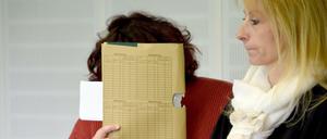 Eine 50 Jahre alte Angeklagte versteckt am 17.06.2015 im Amtsgericht von Kiel (Schleswig-Holstein), neben ihrer Anwältin Simone Trolldenier, ihr Gesicht hinter einem Aktenordner. Die Frau aus Wismar hat jahrelang mit gefälschten Papieren in verschiedenen Bundesländern als Lehrerin gearbeitet.