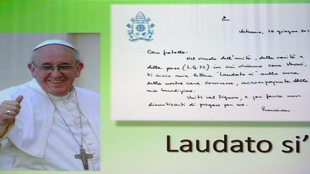 Ein Poster von Papst Franziskus. "Laudato si'" ist der Titel der Umwelt-Enzyklika.