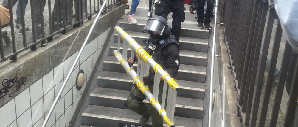 Ein Beamter trägt eine Leiter in die U-Bahn-Station Kochstraße.