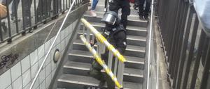Ein Beamter trägt eine Leiter in die U-Bahn-Station Kochstraße.