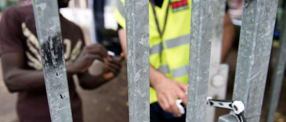 Ein Bewohner zeigt einem privaten Wachmann seinen Berechtigungsausweis, damit dieser das Tor zum Gelände der Kreuzberger Gerhart-Hauptmann-Schule in Berlin öffnet (Juli 2014).
