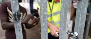 Ein Bewohner zeigt einem privaten Wachmann seinen Berechtigungsausweis, damit dieser das Tor zum Gelände der Kreuzberger Gerhart-Hauptmann-Schule in Berlin öffnet (Juli 2014).