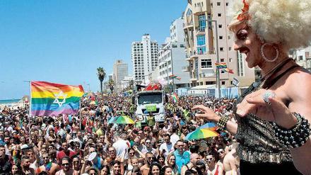Eine Drag Queen steht vor einem jungen, fröhlich wirkenden Publikum auf der Bühne. In der Menge weht eine Regenbogenfahne mit aufgedrucktem Davidstern.