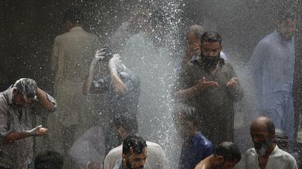 Menschen in Karachi, Pakistan, kühlen sich mit Wasser ab, das aus einem Loch in einer Pipeline schießt. Bisher sind bei der Hitzewelle mehr als tausend Menschen ums Leben gekommen.