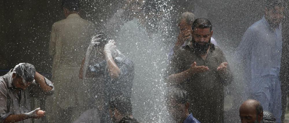 Menschen in Karachi, Pakistan, kühlen sich mit Wasser ab, das aus einem Loch in einer Pipeline schießt. Bisher sind bei der Hitzewelle mehr als tausend Menschen ums Leben gekommen. 