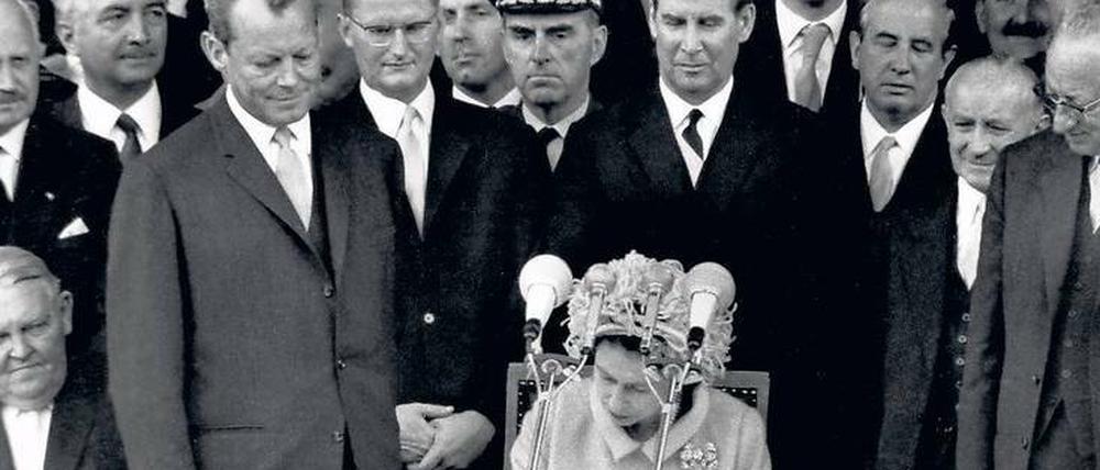 Staatsbesuch. Im Mai 1965 besucht die Queen Berlin. Vor dem Rathaus Schöneberg trägt sie sich – im Beisein des Regierenden Bürgermeisters Willy Brandt – ins Goldene Buch der Stadt ein.