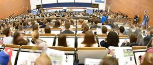 Studierende sitzen in einem Hörsaal und blicken nach vorne.