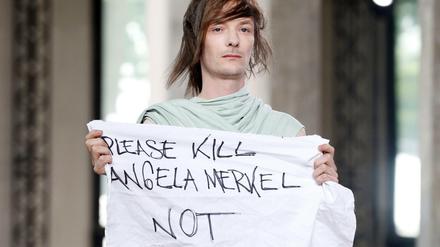 "Please kill Angela Merkel not", steht auf einem Stoff-Banner des Models Jera Diarc auf den Pariser Männermodenschauen im Juni 2015.