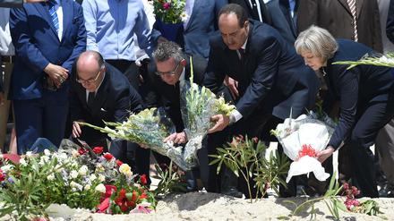 Bundesinnenminister Thomas de Maiziere (2.v.l.), der tunesische Innenminister Mohamed Najem Gharsalli (2.v.r.) und die britische Innenministerin Theresa May legten am Montag am Strand vor dem Imperial Marhaba Hotel in Sousse (Tunesien) Blumen nieder.
