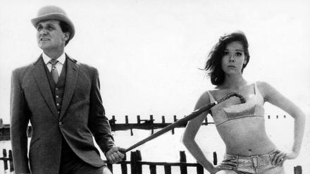 Die britische Schauspielerin Diana Rigg als Geheimagentin "Emma Peel" mit ihrem Partner John Steed, gespielt von Patrick Macnee, in der britischen Erfolgsserie «Mit Schirm, Charme und Melone» (Archivbild vom 30.11.1964).
