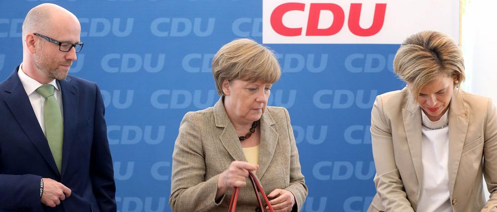 Bundeskanzlerin Angela Merkel und die Fraktionsvorsitzende der CDU im Landtag Rheinland-Pfalz, Julia Klöckner (r), hantieren am 15.06.2015, zu Beginn der Sitzung des Parteivorstands der CDU in Berlin, in ihren Handtaschen. Links schaut der Generalsekretär der Partei, Peter Tauber, interessiert zu.