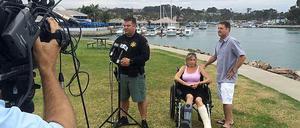 Die Frickmanns mit einem Polizeisprecher. Der Familie ist ein Delfin ins Boot gesprungen und hat der Frau die Knöchel verletzt. 