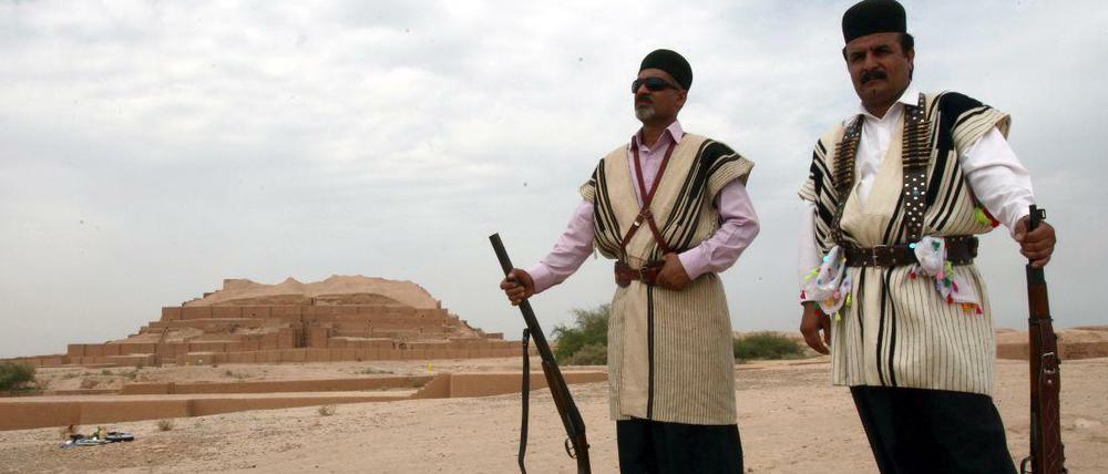 Zwei iranische Männer stehen in traditioneller Kleidung vor einem Ziggurat nahe Susa, das ab heute den Titel Weltkulturerbe trägt.