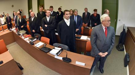 Die Rechtsanwälte und Angeklagten um den Co-Chef der Deutschen Bank, Jürgen Fitschen (hinterste Reihe 2.v.r.), stehen am 23.06.2015 in München (Bayern) zu Beginn des Strafprozessses gegen ihn und vier weitere Ex-Manager der Bank wegen versuchten Betrugs im Kirch-Prozess im Gerichtssaal des Landgerichts München I. In der ersten Reihe steht der ehemalige Chef der Deutschen Bank, Rolf Breuer (r), in der zweiten Reihe (2.v.r.) sein Nachfolger im Amt, Josef Ackermann.