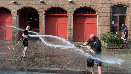 Wet T-Shirt Contest. Schön, wenn sich Angenehmes mit Nützlichem verbindet wie für diese Männer von der Feuerwache in der Oderberger Straße in Prenzlauer Berg. Eine Übung zur Wasserversorgung über lange Strecken gab Gelegenheit zur Abkühlung.