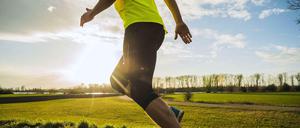 Er hat Abnehmen nicht nötig. Oberkörper und Beine eines schlanken Sportlers beim Joggen auf dem Feldweg.