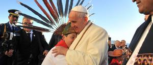 Papst Franziskus umarmt einen Jungen bei seiner Ankunft in Bolivien. Rechts im Bild: Präsident Evo Morales.