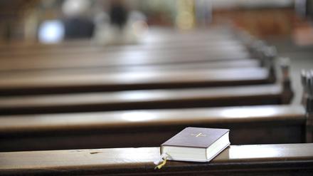Gesangbuch auf einer leeren Kirchenbank in der katholischen Stadtpfarrkirche in Fulda.