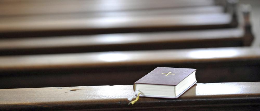 Gesangbuch auf einer leeren Kirchenbank in der katholischen Stadtpfarrkirche in Fulda.