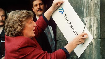 Die scheidende Treuhand-Präsidentin Birgit Breuel entfernt am 30.12.1994 eigenhändig mit einem Schraubenzieher das Firmenschild am Eingang der Treuhandanstalt in Berlin. Auf die Treuhand wurde viel eingedroschen. Doch das war gewollt, wie ein neues Buch des Hamburger Autor Dirk Laabs über das wohl dunkelste Kapitel der Wiedereinigung zeigt. Die Superbehörde diente Bundesregierung und Wirtschaftskonzernen als Sündenbock beim Ausverkauf der DDR. 