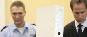 Mit einem Aktenordner vor dem Gesicht kommt am 21.07.2015 in Köln (Nordrhein-Westfalen) ein Angeklagter neben seinem Anwalt Ingmar Rosentreter (r) in den Gerichtssaal. Der Mordprozess gegen einen Mann, der einen anderen wegen eines Streits um eine Pizza erstochen haben soll, hat vor dem Landgericht begonnen.