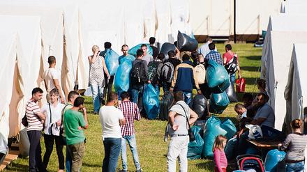 Flüchtlinge ziehen am 15.07.2015 in Hamburg in eine neue Unterkunft im Stadtteil Jenfeld ein. Der wachsende Zustrom von Flüchtlingen zwingt die Stadt Hamburg zu Notmaßnahmen. Hamburgs Sozialsenator Scheele (SPD) schlägt vor, Flüchtlinge vermehrt dort unterzubringen, wo viele Wohnungen leer stehen oder gar abgerissen werden - etwa in Teilen des Ruhrgebiets oder der neuen Länder.
