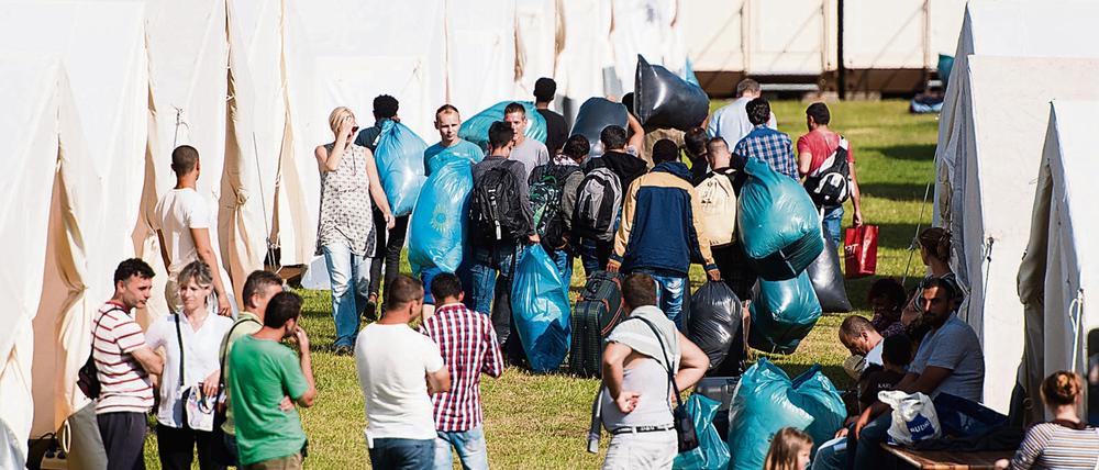 Flüchtlinge ziehen am 15.07.2015 in Hamburg in eine neue Unterkunft im Stadtteil Jenfeld ein. Der wachsende Zustrom von Flüchtlingen zwingt die Stadt Hamburg zu Notmaßnahmen. Hamburgs Sozialsenator Scheele (SPD) schlägt vor, Flüchtlinge vermehrt dort unterzubringen, wo viele Wohnungen leer stehen oder gar abgerissen werden - etwa in Teilen des Ruhrgebiets oder der neuen Länder.