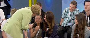 Bundeskanzlerin Angela Merkel (CDU) beugt sich am 15.07.2015 während der Veranstaltung in der von der Regierung gestarteten Gesprächsreihe "Gut leben in Deutschland" in Rostock zu einem Flüchtlingsmädchen palästinensischer Abstammung. Merkels Begegnung mit dem Kind hat in Sozialen Netzwerken zu Kritik geführt.