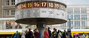 Touristen und Berliner treffen sich unter der Urania-Weltzeituhr auf dem Alexanderplatz in Berlin. 