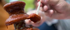 Ein Besucher tunkt am Sonntag bei der Deutschen Grill- und BBQ-Meisterschaft in Hennef (Nordrhein-Westfalen) ein Stück Wurst in einen Brunnen mit Currysoße. Ingesamt brutzelten rund 40 Teams um den Titel.