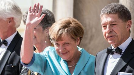 Bundeskanzlerin Angela Merkel (CDU) winkt neben Ehemann Joachim Sauer vor der Eröffnung der 104. Bayreuther Festspiele in Bayreuth.
