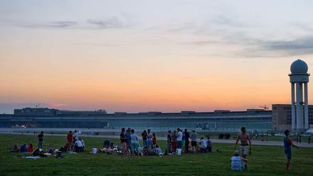 Junge Leute sitzen abends auf dem Tempelhofer Feld.