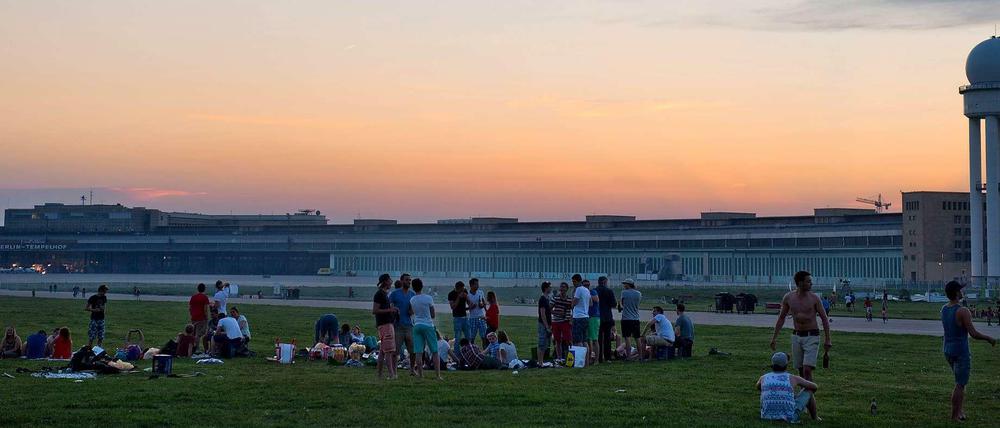 Junge Leute sitzen abends auf dem Tempelhofer Feld.