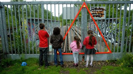 Kinder schauen durch einen Gitterzaun beim Park am Gleisdreieck.