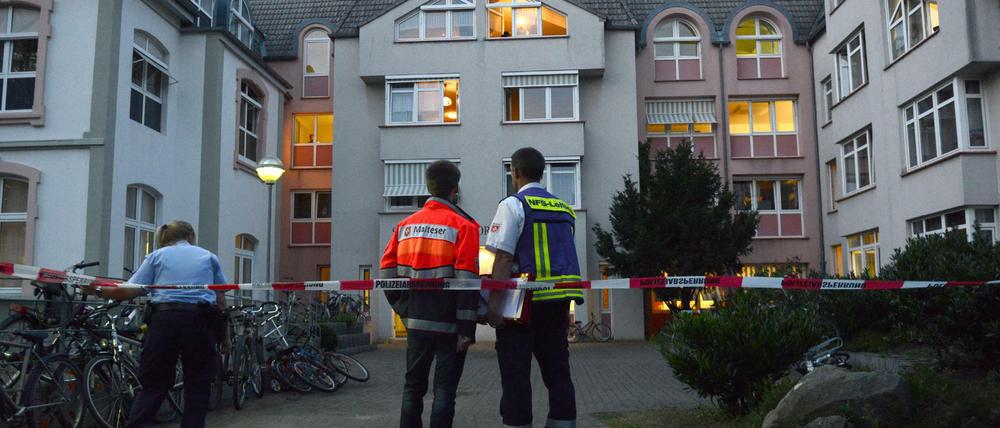 Zwei Männer von der Notfallseelsorge stehen am 01.08.2015 vor einem Flüchtlingsheim in Bonn (Nordrhein-Westfalen). Nach einem Streit zwischen zwei Bewohnern hatte ein Spezialeinsatzkommando (SEK) der Polizei auf den Angreifer geschossen und ihn schwer verletzt. 
