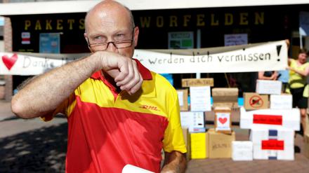 Der Paketzusteller Helmut Becker wischt sich am 03.08.2015 in Worfelden (Gemeinde Büttelborn, Hessen) die Tränen aus den Augen. Nach fast drei Jahrzehnten hat der von vielen als "bester Paketbote aller Zeiten" bezeichnete Post-Mitarbeiter seine letzte Tour absolviert.
