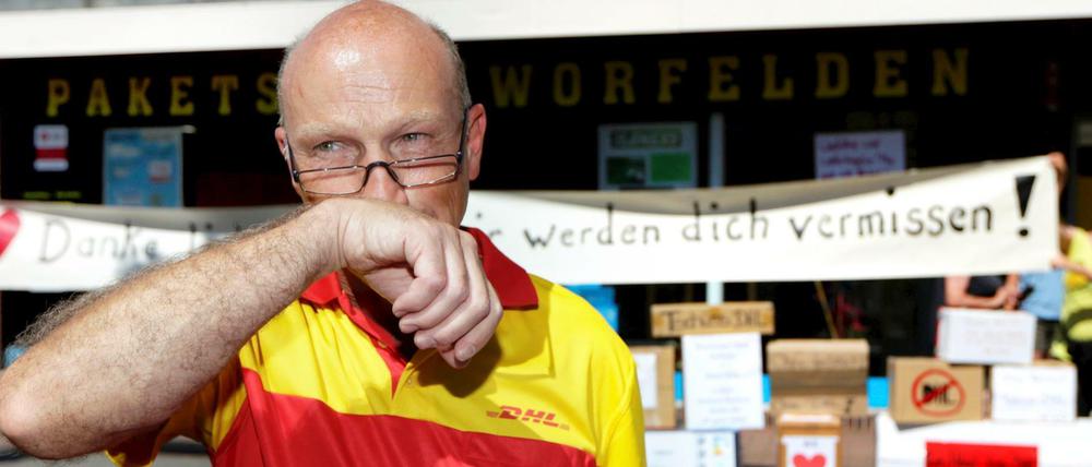 Der Paketzusteller Helmut Becker wischt sich am 03.08.2015 in Worfelden (Gemeinde Büttelborn, Hessen) die Tränen aus den Augen. Nach fast drei Jahrzehnten hat der von vielen als "bester Paketbote aller Zeiten" bezeichnete Post-Mitarbeiter seine letzte Tour absolviert.