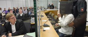Mit einem Aktenordner verdeckt Ayoub B. (27) beim Prozessauftakt in Celle sein Gesicht. 