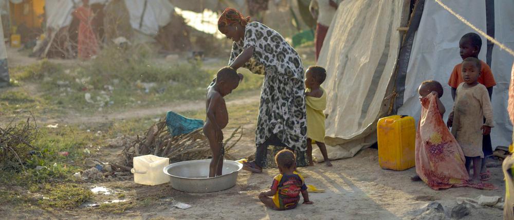 Eine Mutter badet Kinder in einem Flüchtlingscamp in Somalia. 