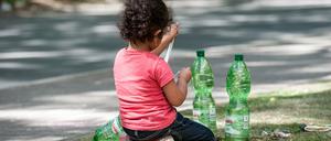 Ein Flüchtlingskind sitzt am 06.08.2015 in Berlin auf dem Gelände des Landesamtes für Gesundheit und Soziales (LaGeSo) auf einem Grünstreifen. 