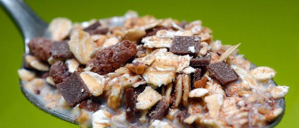 Ein Löffel mit Müsli, bestehend aus Getreide-Flocken, Schokolade und Mais-Pops. Fitness-Frühstück, Müsli-Riegel, Bio-Drink: Oft steckt mehr Fett, Zucker oder Salz drin als gedacht. 