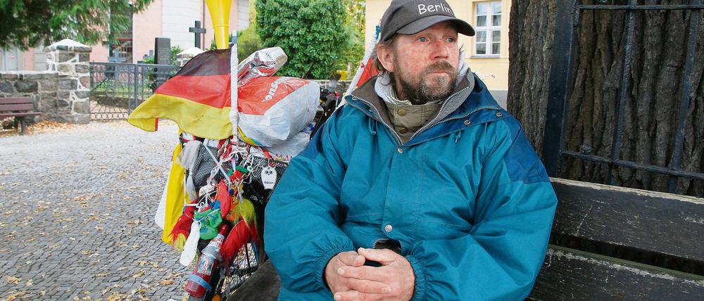 Peter, ein wohnungsloser Zehlendorfer; in seinem "Wohnzimmer" vor der Dorfkirche, der Friedenseiche und der alten Dorfschule in Zehlendorf-Mitte.