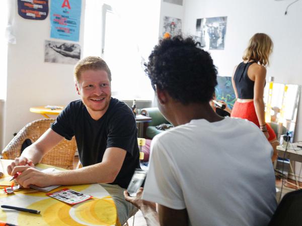 Am WG-Tisch. Bartholomäus und Youssouf besprechen den Alltag.