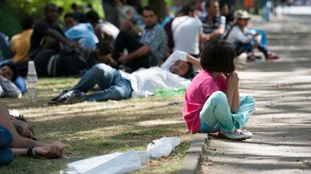 Ein Flüchtlingskind sitzt in Berlin auf dem Gelände des Landesamtes für Gesundheit und Soziales (LaGeSo) auf einem Bordstein. Auch die Helfer sind langsam am Ende ihrer Kräfte.