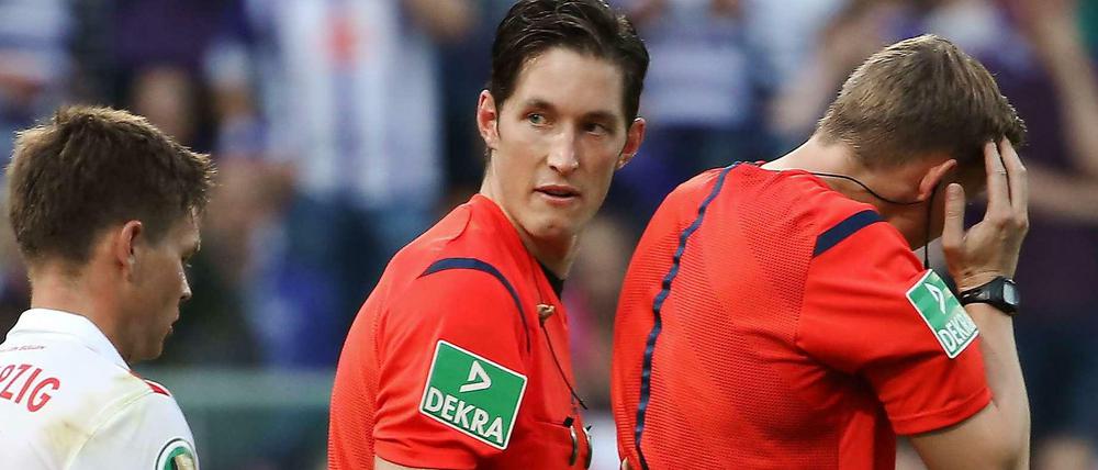 Schiedsrichter Petersen (r.) brach das Spiel ab, nachdem er von einem Feuerzeug am Kopf getroffen worden war.